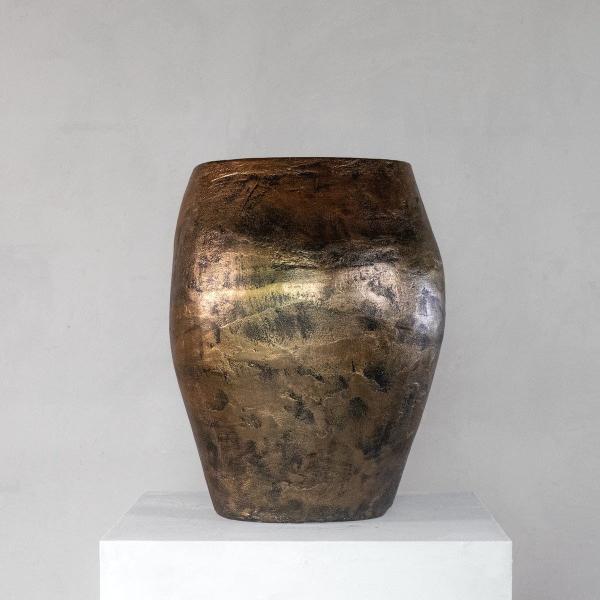 A handmade sculptural stool with a feminine curvy shape and finished with a metallic bronze rough texture.