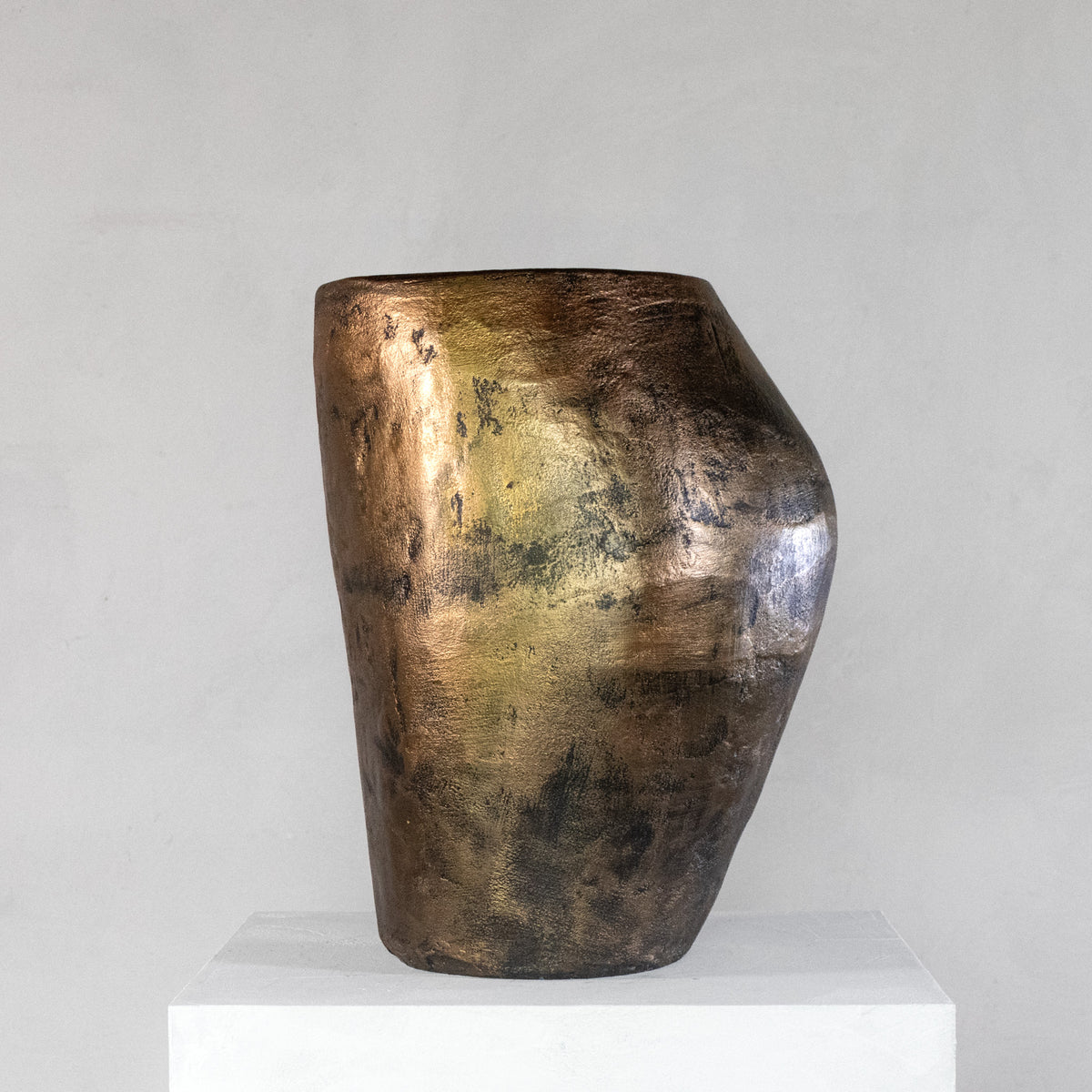 A handmade sculptural stool with a feminine curvy shape and finished with a metallic bronze rough texture.