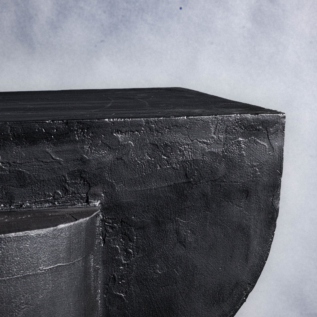 A close-up of a dark charcoal stone texture of a closet corner, showing a rough, matte surface and a curved edge.
