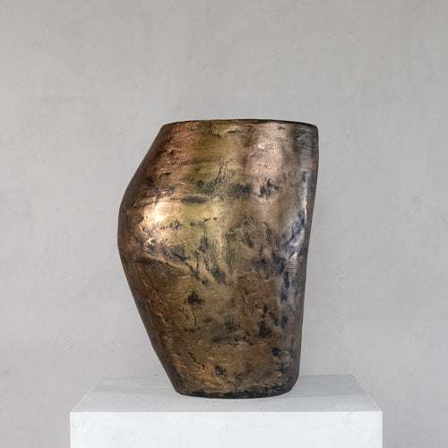 A handmade sculptural stool with a feminine curvy shape and finished with a metallic bronze rough texture.