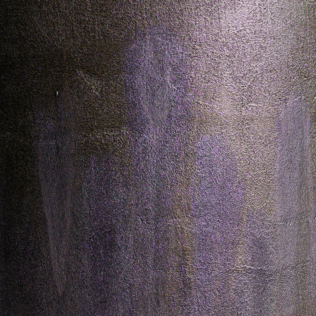 A close-up of a textured surface with a mottled pattern of dark gray, black, and muted purple.